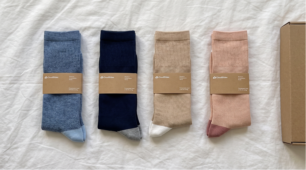 Four pairs of compression socks and a shipping box laid out on a white sheet